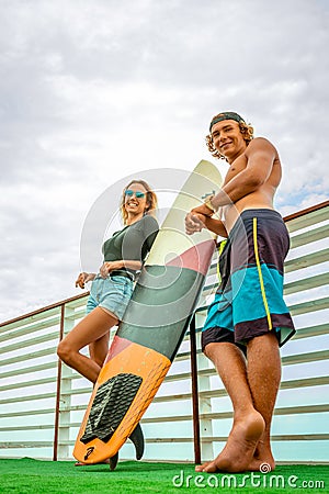 Smiling young active couple surfers relaxing on the beach after sport with Surfboard. Healthy Lifestyle. Extreme Water Stock Photo