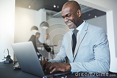 Smiling young African American businessman working on a laptop Stock Photo