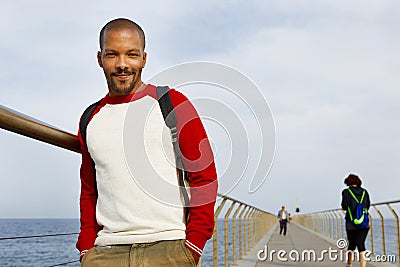 Smiling young African-American hipster walking summer day on the beach outside of the city. Stock Photo