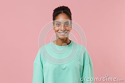 Smiling young african american woman girl in green sweatshirt posing isolated on pastel pink background studio portrait Stock Photo