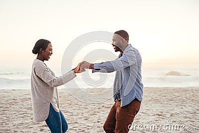 Smiling young African couple dancing on a beach at sunset Stock Photo