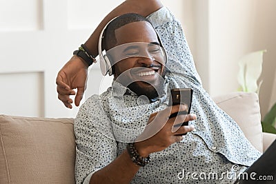 Smiling young african man wearing headphones listen to mobile music Stock Photo