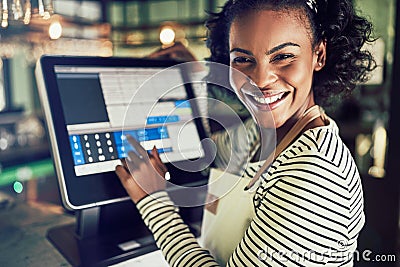 Smiling young waitress using a restaurant point of sale terminal Stock Photo