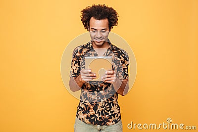 Smiling young afro american guy standing and using pc tablet Stock Photo