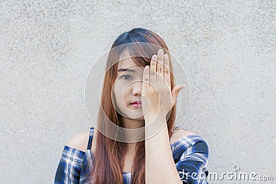 Smiling young beautiful asian woman closing her eyes with hands on concrete wall background Stock Photo
