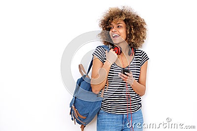 Smiling young black woman with mobile phone headphones and bag against white background Stock Photo