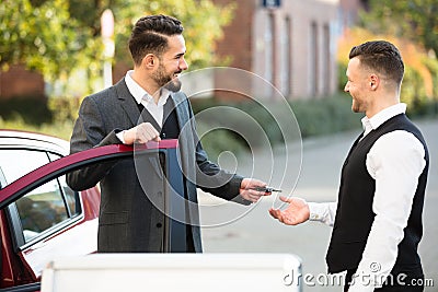 Young Businessman Giving Car Key To Valet Stock Photo