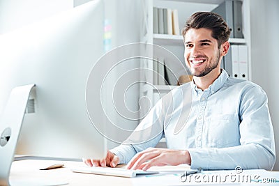 Smiling young businessman using laptop computer in office Stock Photo