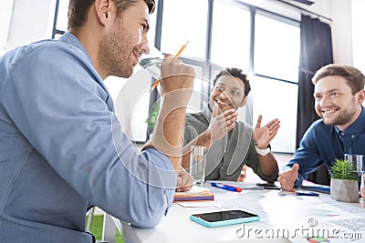 Smiling young businessmen drinking water and discussing new project Stock Photo