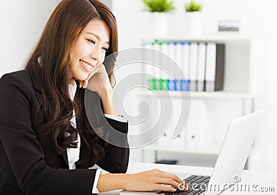 Smiling young businesswoman working with laptop Stock Photo