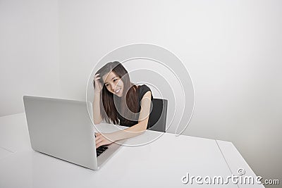 Smiling young businesswoman working on laptop at office desk Stock Photo