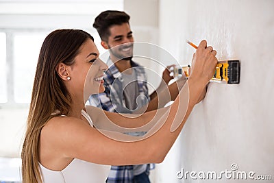 Smiling young couple measuring wall with level tool, renovation Stock Photo