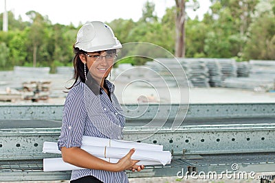 Smiling young engineer woman with rolled drawings Stock Photo