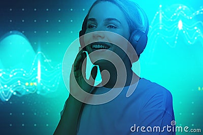 Smiling young European woman in headphones blue background Stock Photo