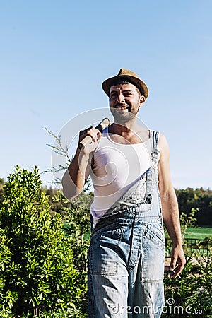 Smiling young farmer man standing in the garden while looking away Stock Photo