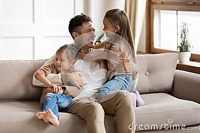 Smiling young father playing with small cute kids daughters. Stock Photo