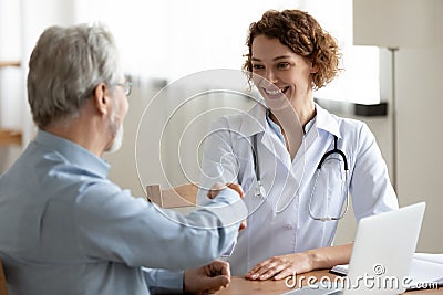 Smiling female doctor handshaking greeting healthy senior male patient Stock Photo