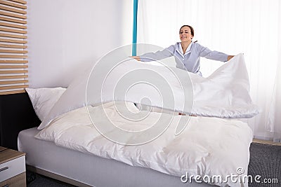 Housekeeper Arranging Bedsheet On Bed Stock Photo
