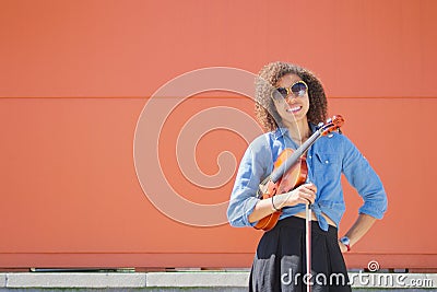 Smiling young female violinist holding violin and bow Stock Photo