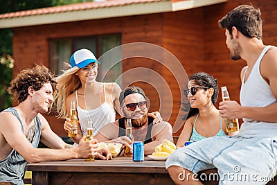 Smiling young friends sitting and drinking beer outdoors Stock Photo