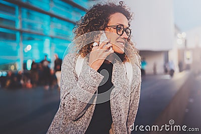 Smiling young girl calling with her cell telephone while standing at night on the street. Bokeh and flares effect on Stock Photo