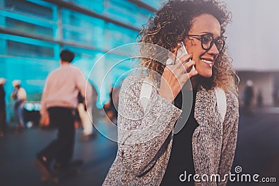 Smiling young girl calling with her cell telephone while standing at night on the street. Bokeh and flares effect on Stock Photo