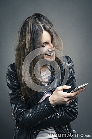 Smiling young girl looking at phone with amused emotion Stock Photo