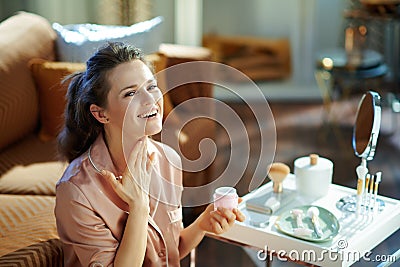 Smiling woman with jar applying neck cream Stock Photo