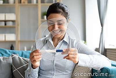 Smiling young indian girl holding ovulation test, looking at result. Stock Photo