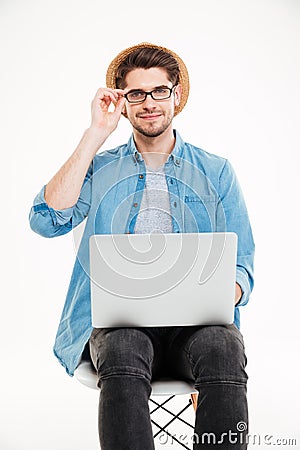 Smiling young man in glasses and hat using laptop Stock Photo