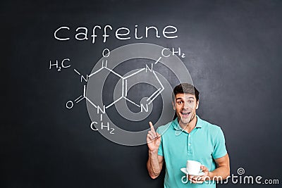 Smiling young man pointing on drawn caffeine molecule chemical structure Stock Photo