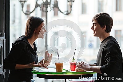 Smiling young man sitting in cafe with sister drinking juice Stock Photo