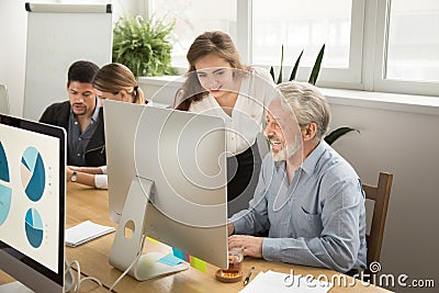 Smiling young manager helping senior worker with computer office Stock Photo