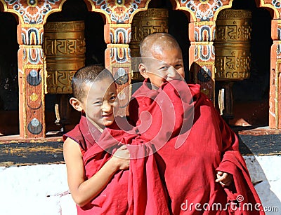 Smiling young monks standing by the religious prayer wheels at Paro Rinpung dzong, Paro, Bhutan Editorial Stock Photo