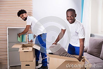 Movers Unpacking The Cardboard Boxes In The Home Stock Photo