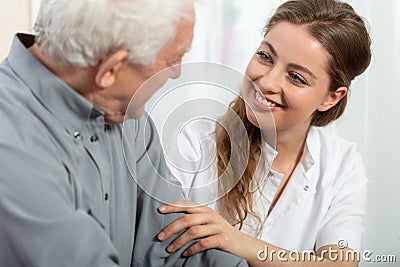 Smiling nurse sitting at table with senior patient Stock Photo