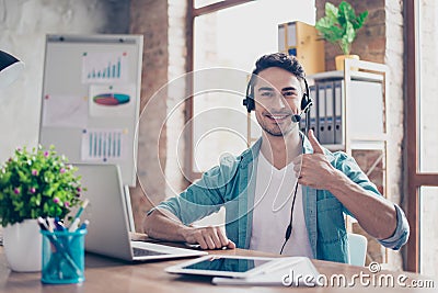 Smiling young operator of call center sitting at the table and s Stock Photo