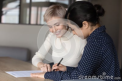 Smiling young professional insurer showing place for signature to client. Stock Photo