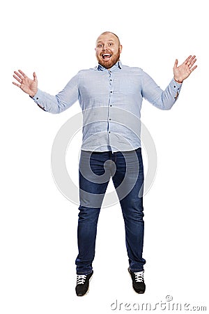 A smiling young redhead man in a blue shirt and jeans is jumping. Full height. Isolated over white background. Stock Photo