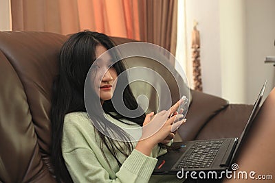 Smiling young teen girl sitting on sofa at home Stock Photo