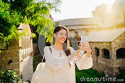 Smiling young tourist making selfie with smartphone in front of historic landmark in old town in Mostar, Bosnia and Herzegovina. Stock Photo