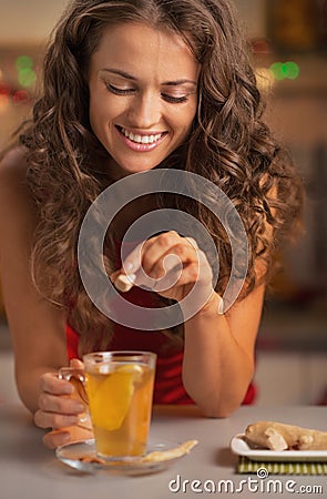 Smiling young woman adding cane sugar cube in ginger tea Stock Photo