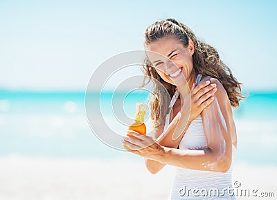 Smiling young woman applying sun block creme on beach Stock Photo