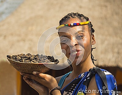 Smiling young woman Bantu nation serving eatable caterpillars for dinner. South Africa. Editorial Stock Photo