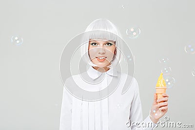 Smiling young woman in blonde wig holding fake ice cream Stock Photo