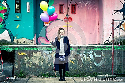 Smiling young woman with colorful balloons at urban industrial b Stock Photo