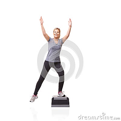 Reaching her fitness goals. A smiling young woman doing aerobics on an aerobic step against a white background - K-step. Stock Photo