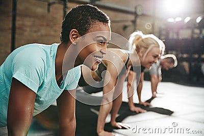 Smiling young woman doing pushups in a gym exercise class Stock Photo