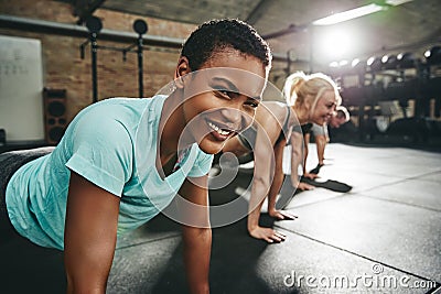 Smiling young woman doing pushups during a gym workout session Stock Photo