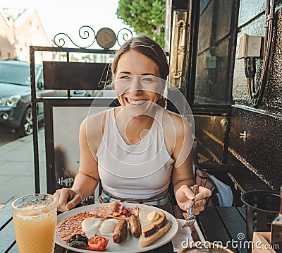 Smiling young woman eating an english breakfast Stock Photo